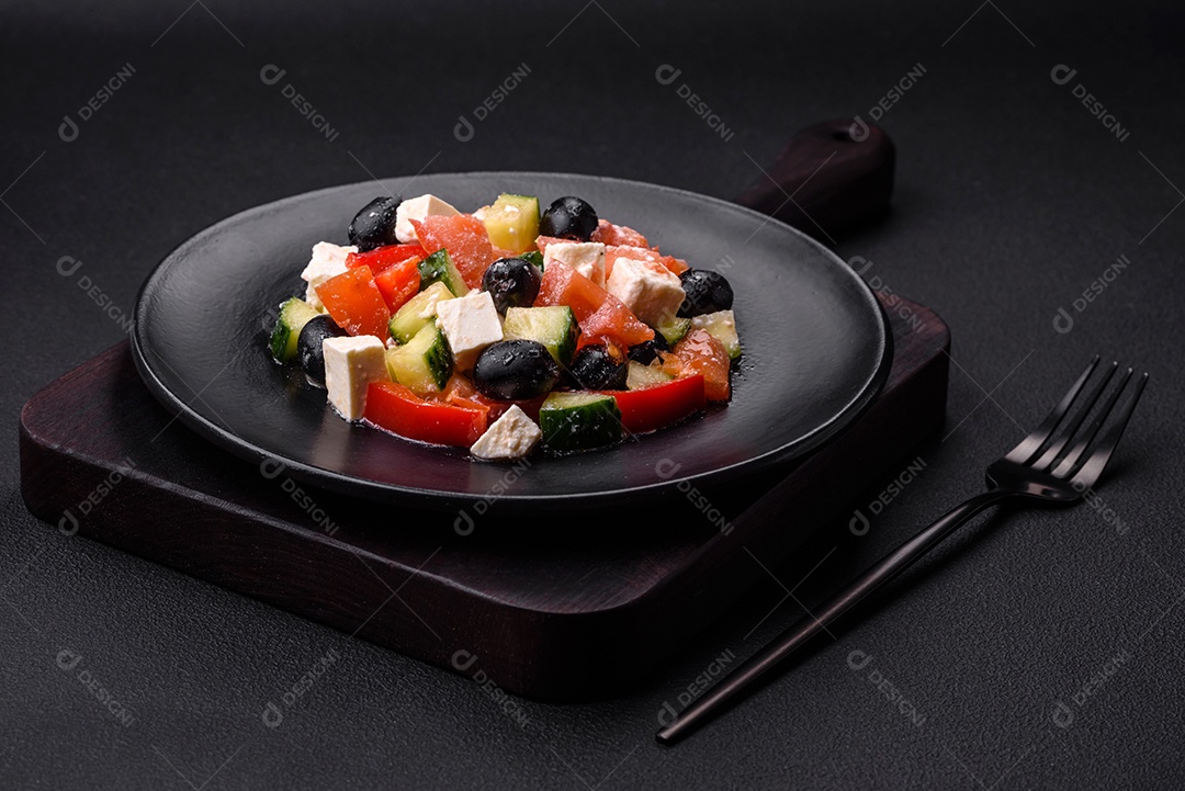 Deliciosa salada grega fresca com azeitonas, tomates, pepinos, queijo feta, especiarias, ervas e azeite num prato cerâmico preto