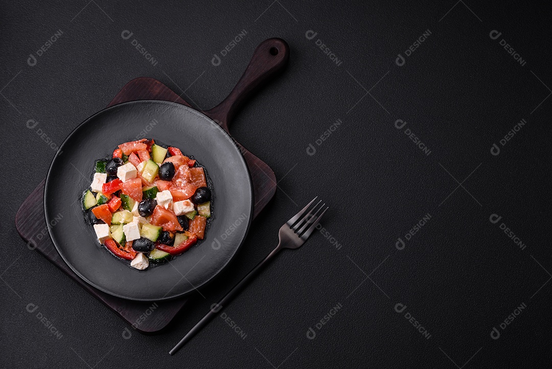 Deliciosa salada grega fresca com azeitonas, tomates, pepinos, queijo feta, especiarias, ervas e azeite num prato cerâmico preto