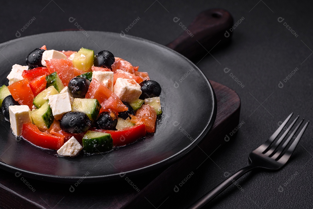 Deliciosa salada grega fresca com azeitonas, tomates, pepinos, queijo feta, especiarias, ervas e azeite num prato cerâmico preto