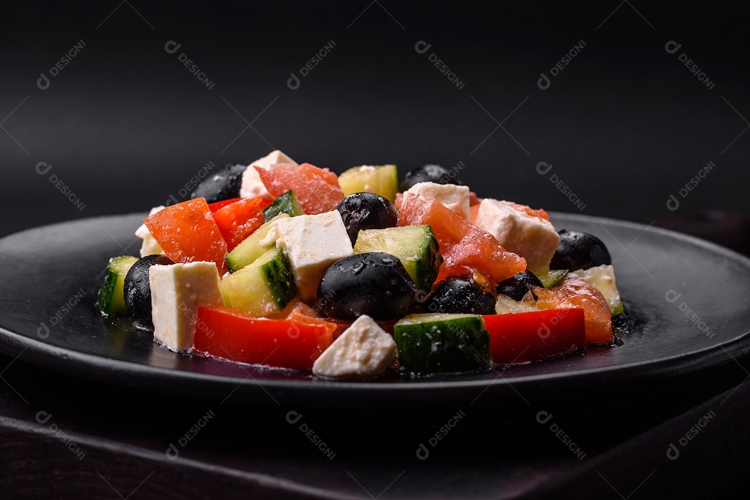 Deliciosa salada grega fresca com azeitonas, tomates, pepinos, queijo feta, especiarias, ervas e azeite num prato cerâmico preto