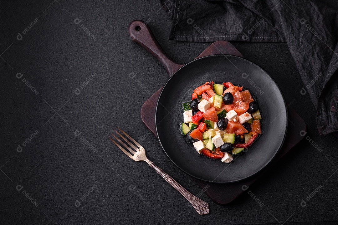 Deliciosa salada grega fresca com azeitonas, tomates, pepinos, queijo feta, especiarias, ervas e azeite num prato cerâmico preto