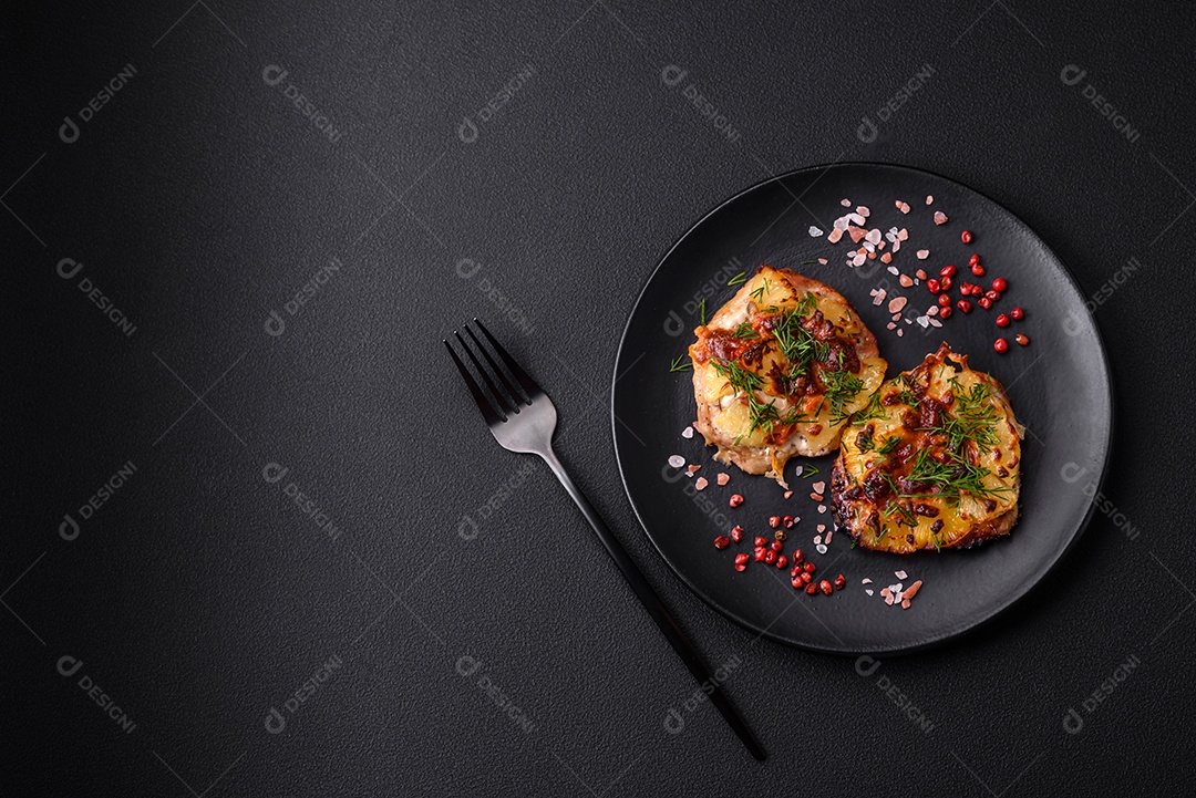 Carne assada no forno com abacaxi, tomate, queijo, especiarias e ervas em uma placa de cerâmica preta sobre fundo escuro de concreto