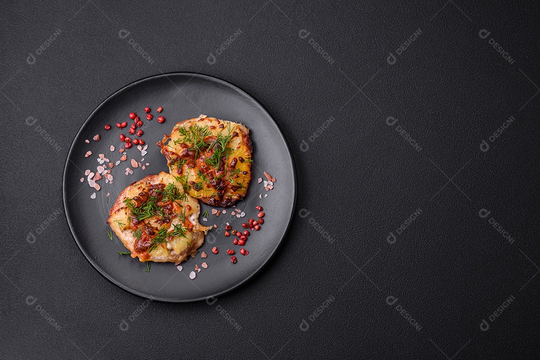 Carne assada no forno com abacaxi, tomate, queijo, especiarias e ervas em uma placa de cerâmica preta sobre fundo escuro de concreto