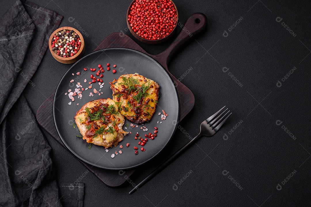 Carne assada no forno com abacaxi, tomate, queijo, especiarias e ervas em uma placa de cerâmica preta sobre fundo escuro de concreto