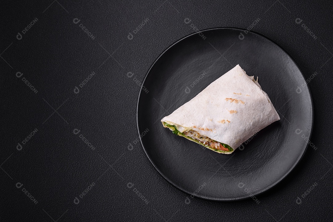 Delicioso pão fresco com frango, tomate, alface e pepino em pão pita sobre um fundo escuro de concreto