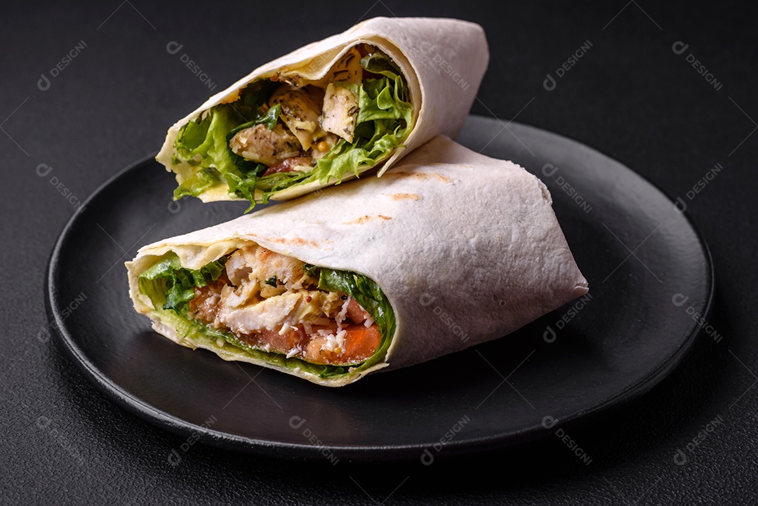 Delicioso pão fresco com frango, tomate, alface e pepino em pão pita sobre um fundo escuro de concreto