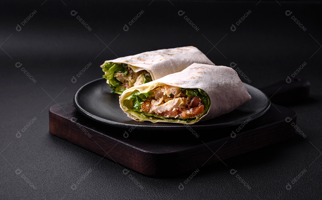 Delicioso pão fresco com frango, tomate, alface e pepino em pão pita sobre um fundo escuro de concreto