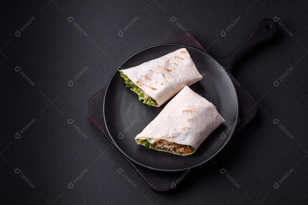 Delicioso pão fresco com frango, tomate, alface e pepino em pão pita sobre um fundo escuro de concreto