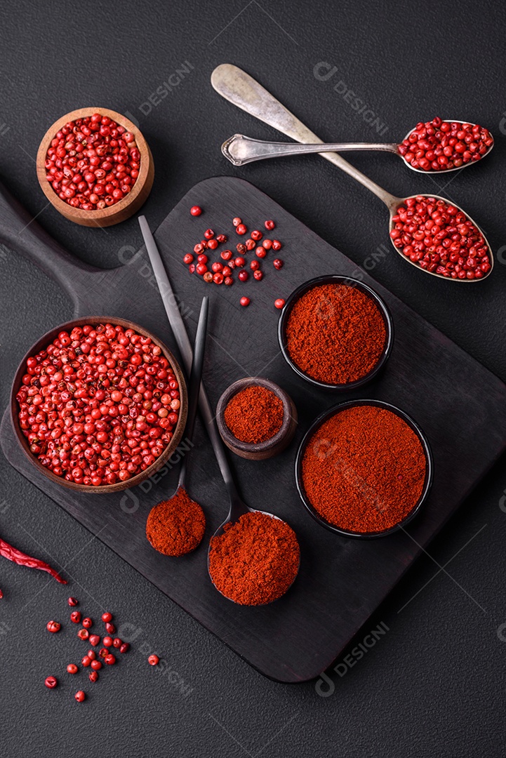 Tempere a páprica defumada em forma de pó em tigelas e colheres sobre um fundo escuro de concreto. Ingredientes da culinária asiática