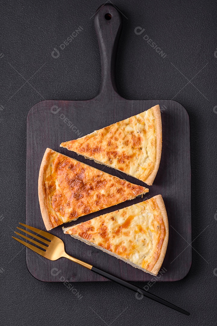 Linda e deliciosa torta de quiche com quatro tipos de queijo com especiarias e ervas em um fundo escuro de concreto