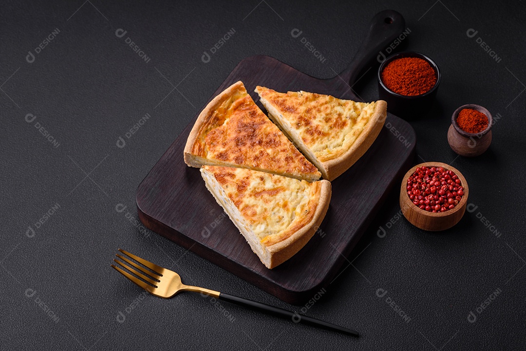 Linda e deliciosa torta de quiche com quatro tipos de queijo com especiarias e ervas em um fundo escuro de concreto