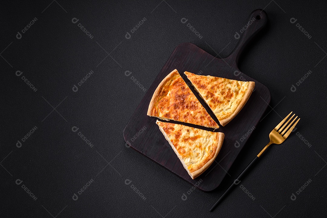 Linda e deliciosa torta de quiche com quatro tipos de queijo com especiarias e ervas em um fundo escuro de concreto