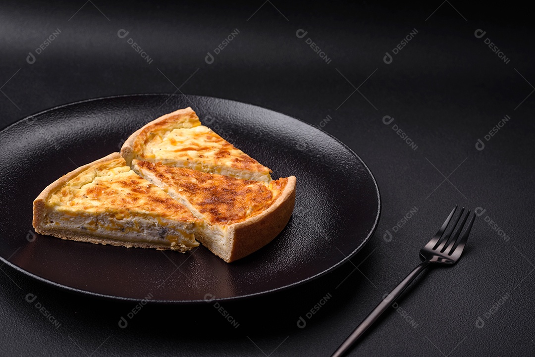 Linda e deliciosa torta de quiche com quatro tipos de queijo com especiarias e ervas em um fundo escuro de concreto