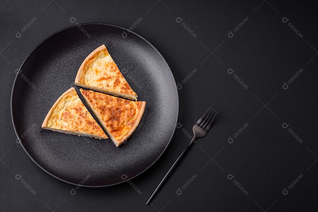 Linda e deliciosa torta de quiche com quatro tipos de queijo com especiarias e ervas em um fundo escuro de concreto
