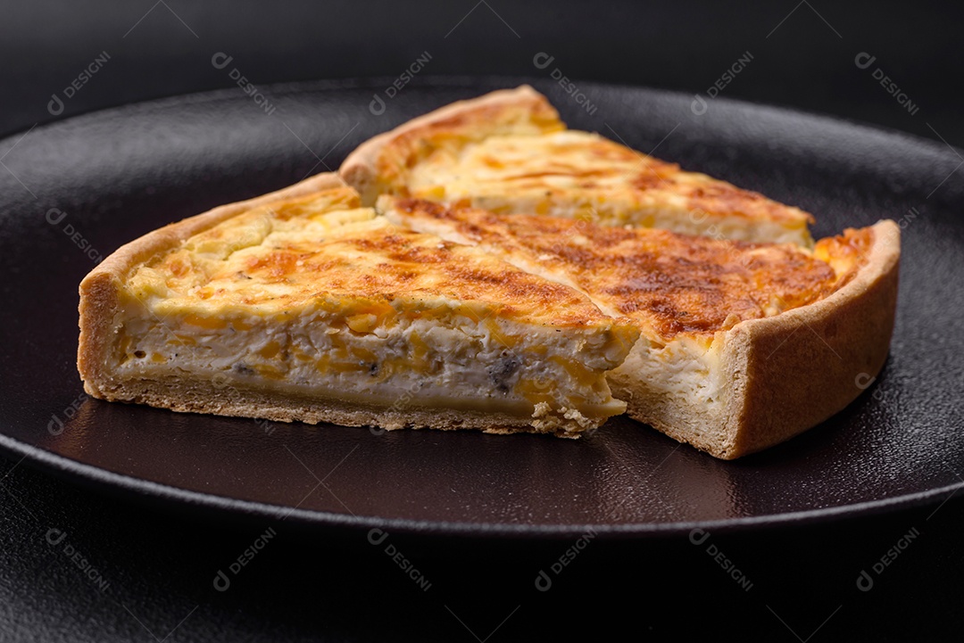 Linda e deliciosa torta de quiche com quatro tipos de queijo com especiarias e ervas em um fundo escuro de concreto