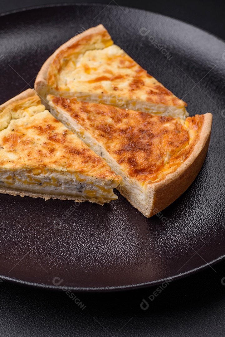 Linda e deliciosa torta de quiche com quatro tipos de queijo com especiarias e ervas em um fundo escuro de concreto