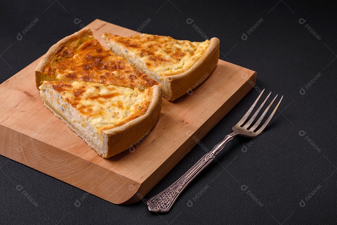 Linda e deliciosa torta de quiche com quatro tipos de queijo com especiarias e ervas em um fundo escuro de concreto