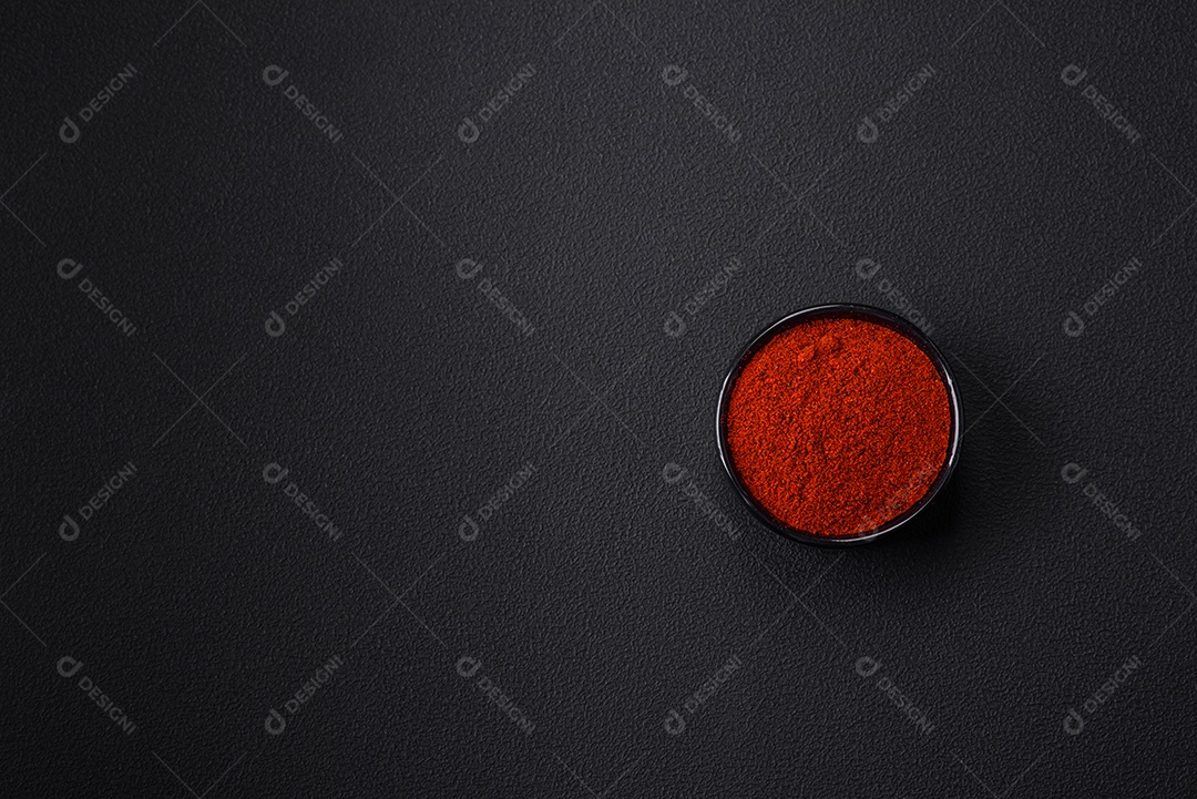 Tempere a páprica defumada em forma de pó em tigelas e colheres sobre um fundo escuro de concreto. Ingredientes da culinária asiática