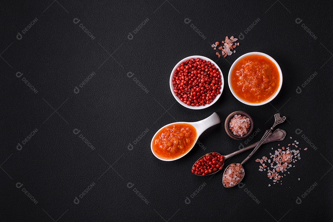 Molho adjika vermelho ou ketchup com especiarias e ervas sobre um fundo escuro de concreto