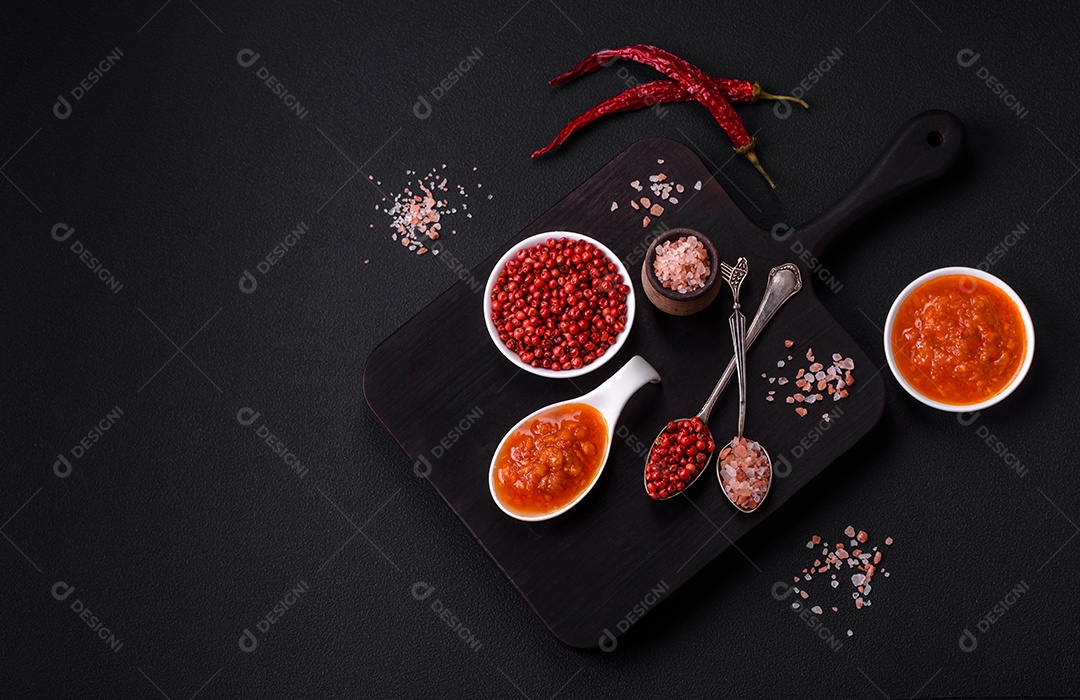 Molho adjika vermelho ou ketchup com especiarias e ervas sobre um fundo escuro de concreto