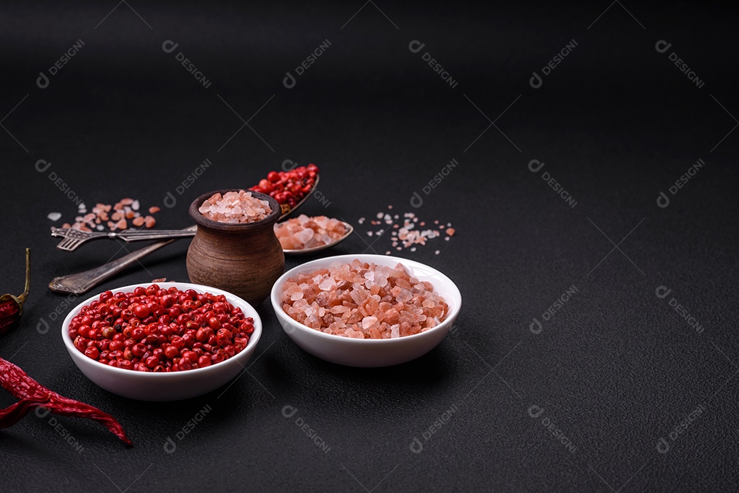 Sal rosa do Himalaia em uma tigela de madeira sobre um fundo escuro de concreto. Temperos e aditivos na cozinha