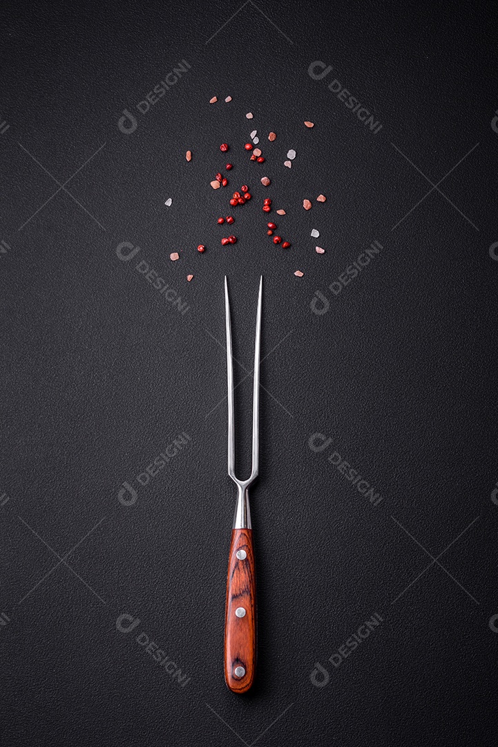 Garfo sobre mesa de concreto preto com pimenta rosa e sal do Himalaia. Pode ser usado como plano de fundo