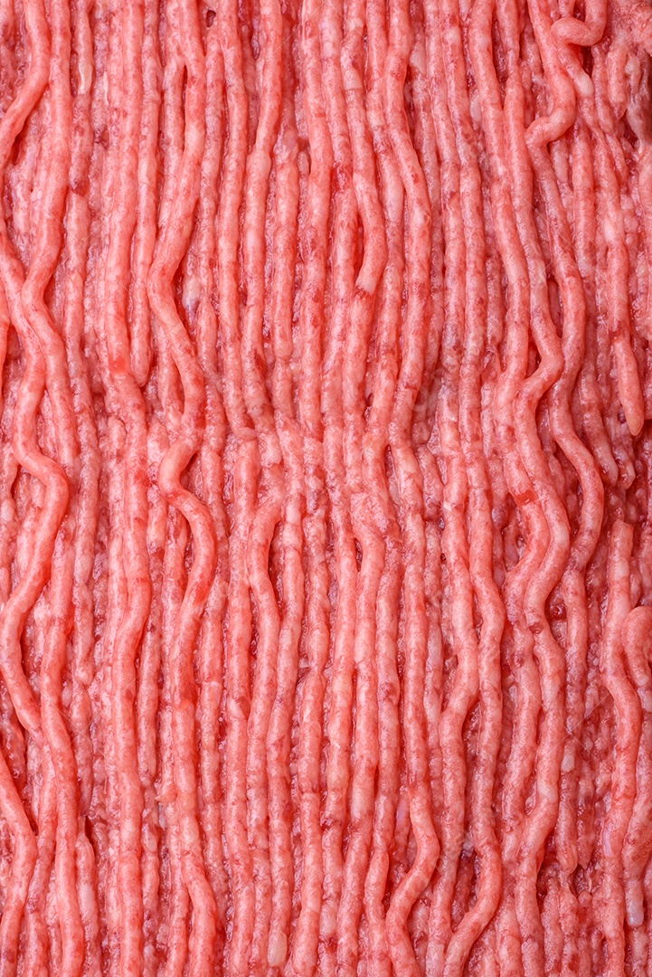 Carne crua ou carne de porco picada com especiarias salgadas e ervas em uma tábua de madeira sobre um fundo escuro de concreto