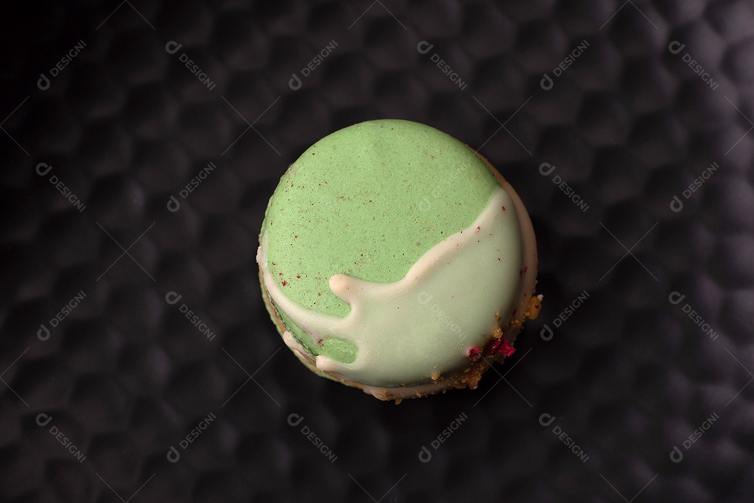 Lindo macaron saboroso com recheio e sabor de frutas em uma placa preta sobre um fundo escuro de concreto
