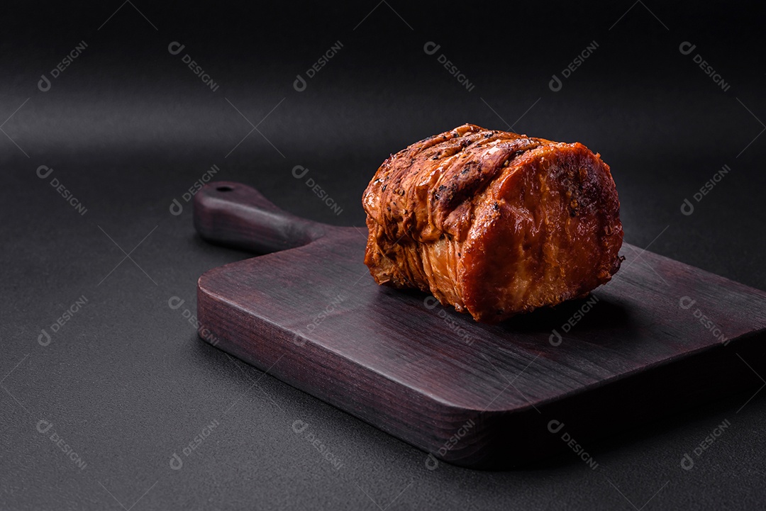 Deliciosa carne ou presunto fresco defumado com especiarias e ervas sobre um fundo escuro de concreto