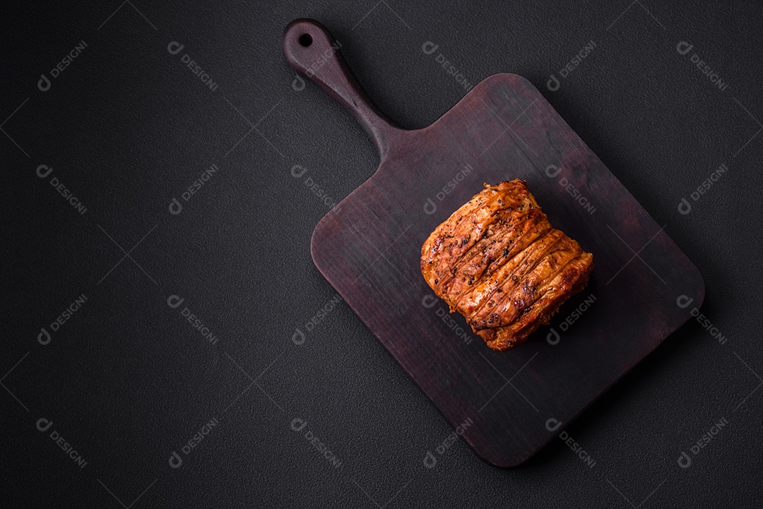 Deliciosa carne ou presunto fresco defumado com especiarias e ervas sobre um fundo escuro de concreto