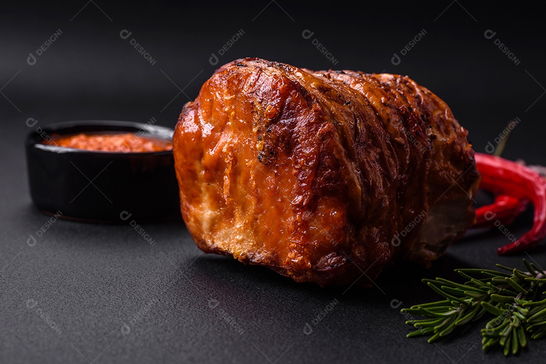 Deliciosa carne ou presunto fresco defumado com especiarias e ervas sobre um fundo escuro de concreto