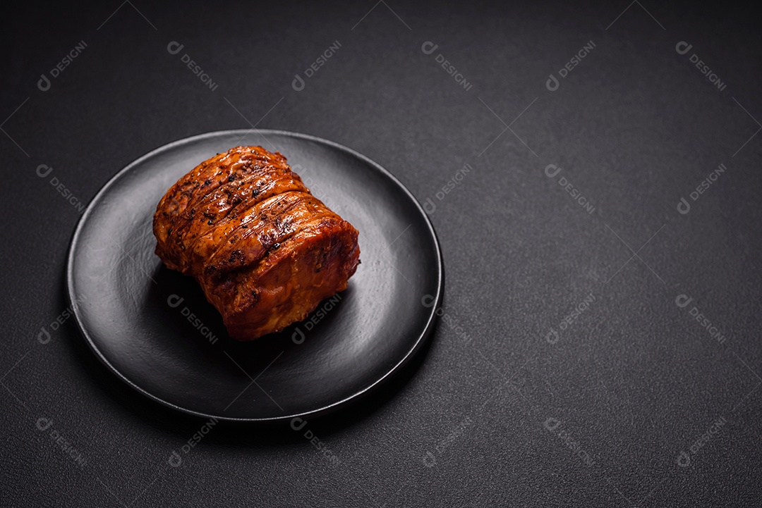 Deliciosa carne ou presunto fresco defumado com especiarias e ervas sobre um fundo escuro de concreto