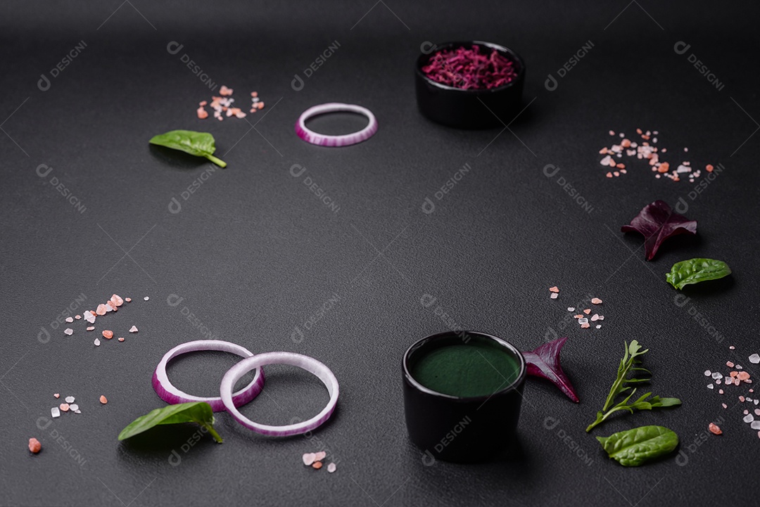 Deliciosa salada fresca composta por espinafre, acelga, radicchio, gráfico vermelho, sangue de touros e rúcula em uma placa preta sobre um fundo escuro de concreto