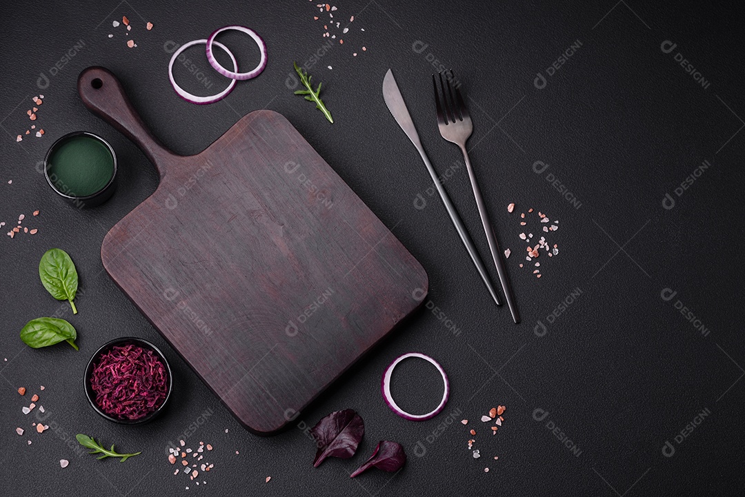 Deliciosa salada fresca composta por espinafre, acelga, radicchio, gráfico vermelho, sangue de touros e rúcula em uma placa preta sobre um fundo escuro de concreto