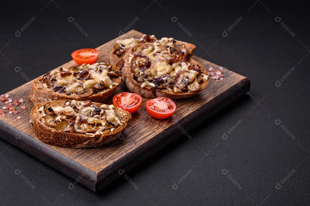 Deliciosa torrada crocante ou bruscheta com cebola frita, cogumelos champignon e queijo com especiarias e ervas sobre um fundo escuro de concreto