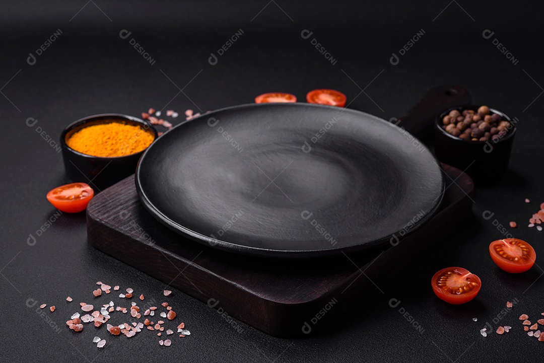 Prato sobre tábua de madeira, especiarias e ervas sobre um fundo escuro de concreto