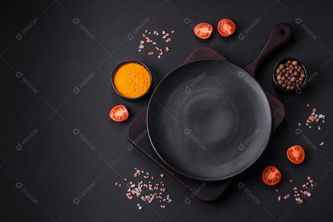 Prato sobre tábua de madeira, especiarias e ervas sobre um fundo escuro de concreto