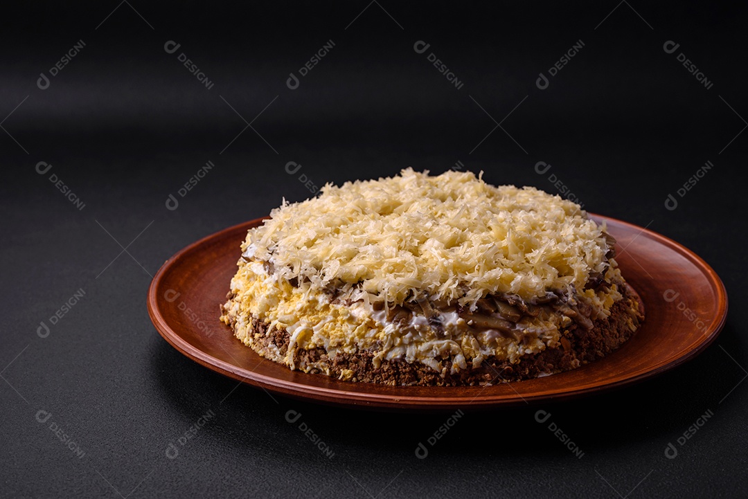 Deliciosa torta fresca com fígado de galinha, ovos, cebola, cenoura e maionese num prato cerâmico sobre um fundo escuro de concreto