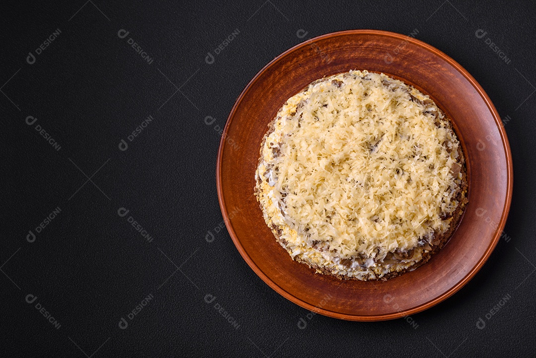 Deliciosa torta fresca com fígado de galinha, ovos, cebola, cenoura e maionese num prato cerâmico sobre um fundo escuro de concreto
