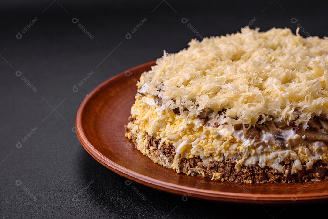 Deliciosa torta fresca com fígado de galinha, ovos, cebola, cenoura e maionese num prato cerâmico sobre um fundo escuro de concreto
