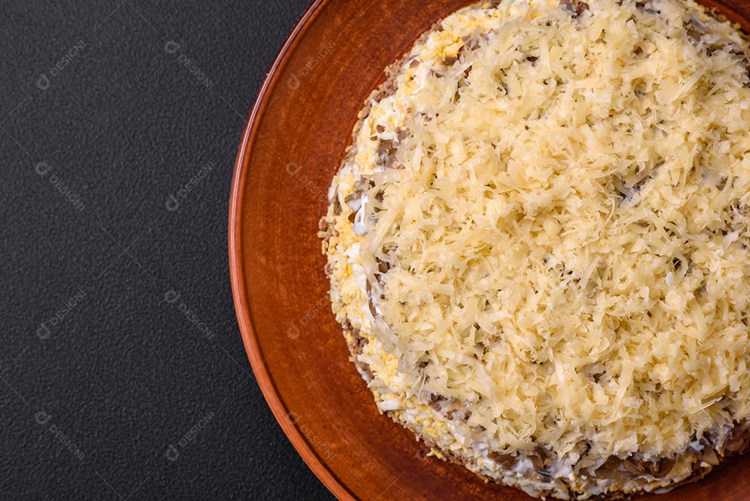 Deliciosa torta fresca com fígado de galinha, ovos, cebola, cenoura e maionese num prato cerâmico sobre um fundo escuro de concreto