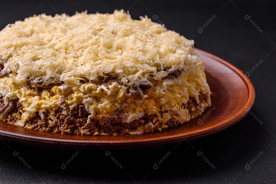 Deliciosa torta fresca com fígado de galinha, ovos, cebola, cenoura e maionese num prato cerâmico sobre um fundo escuro de concreto