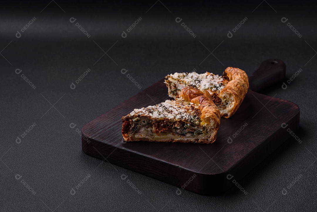 Deliciosa quiche com frango, queijo, ervas, especiarias e ervas sobre um fundo escuro de concreto