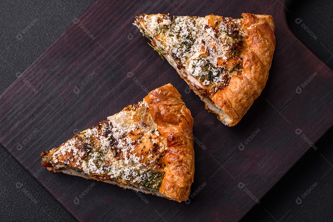 Deliciosa quiche com frango, queijo, ervas, especiarias e ervas sobre um fundo escuro de concreto