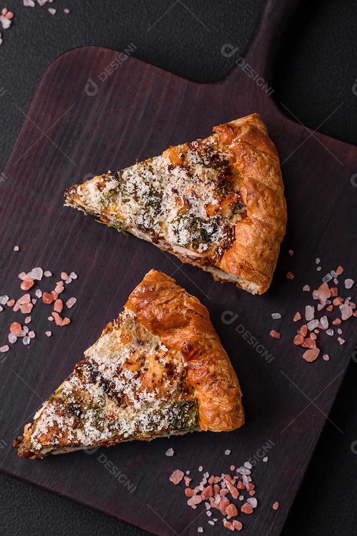 Deliciosa quiche com frango, queijo, ervas, especiarias e ervas sobre um fundo escuro de concreto