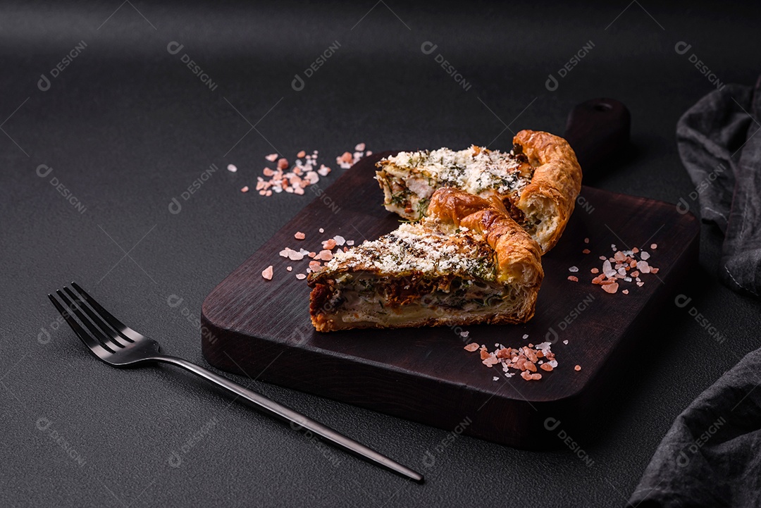 Deliciosa quiche com frango, queijo, ervas, especiarias e ervas sobre um fundo escuro de concreto