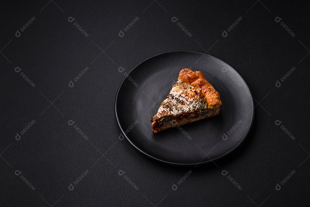 Deliciosa quiche com frango, queijo, ervas, especiarias e ervas sobre um fundo escuro de concreto