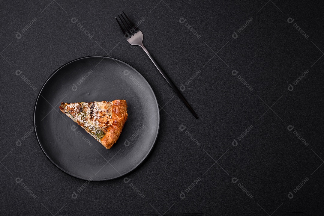 Deliciosa quiche com frango, queijo, ervas, especiarias e ervas sobre um fundo escuro de concreto