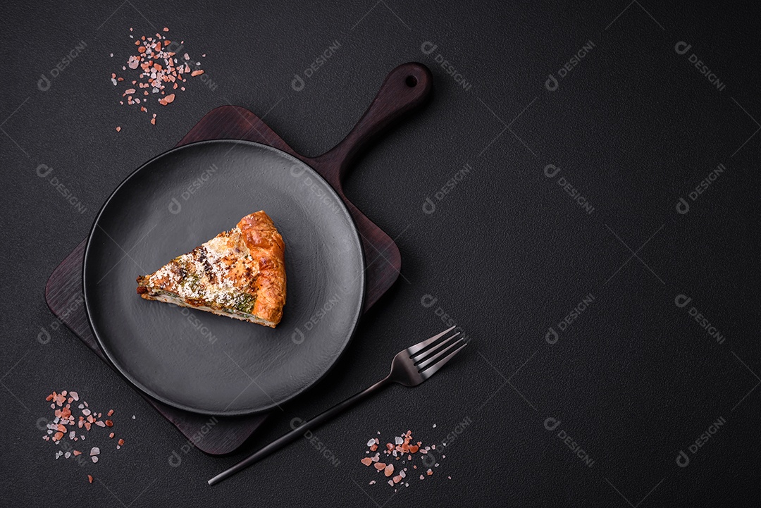 Deliciosa quiche com frango, queijo, ervas, especiarias e ervas sobre um fundo escuro de concreto