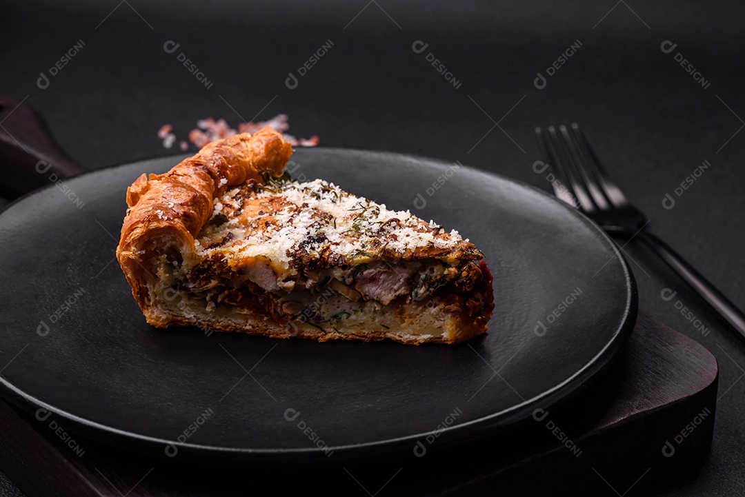 Deliciosa quiche com frango, queijo, ervas, especiarias e ervas sobre um fundo escuro de concreto